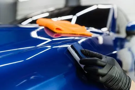Technician applying a protective coating to vehicle paint